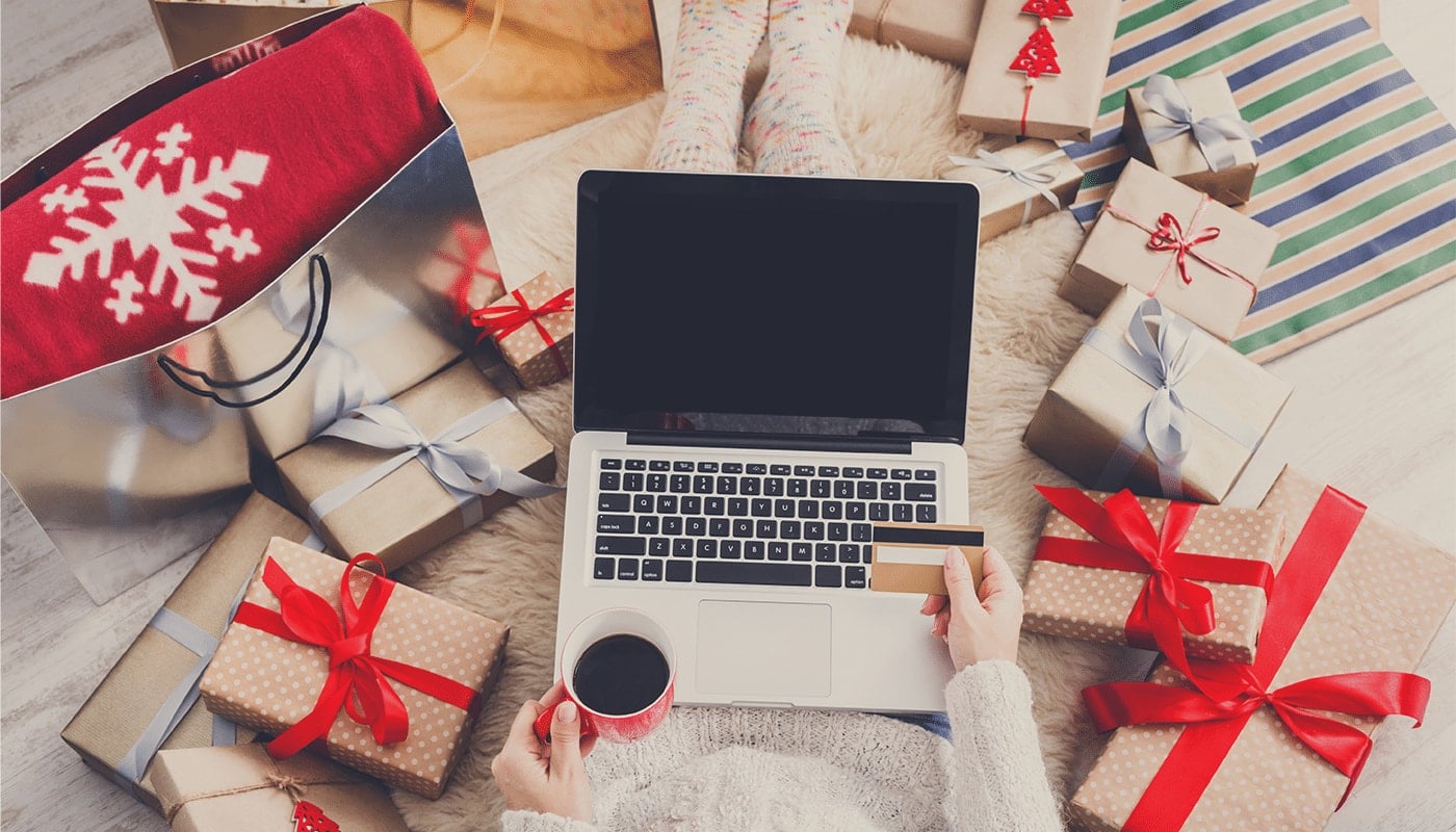 woman holding her coffee and credit card with her laptop on her lap